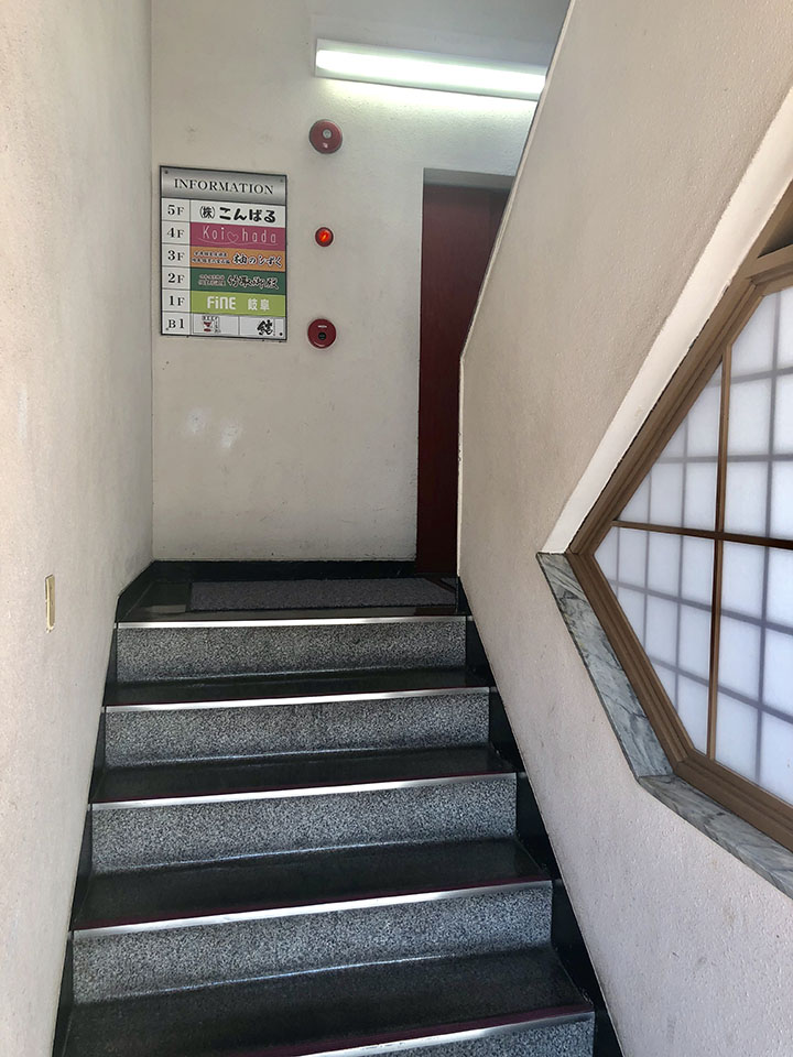 数段階段を登るとエレベーターがあります。ビルの4階に上ります。